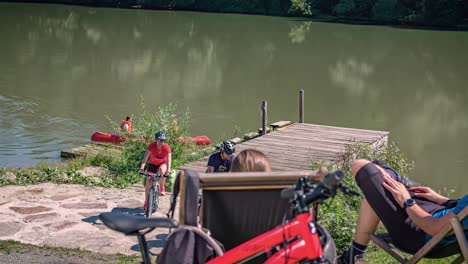 Cyclist-couple-rests-on-shores-of-lake-in-Slovenia