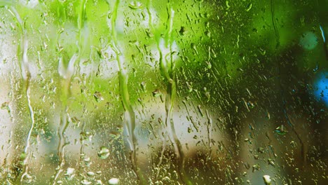 Wassertropfen-Auf-Glasfenster-Mit-Verschwommenen-Grünen-Bäumen-Im-Hintergrund