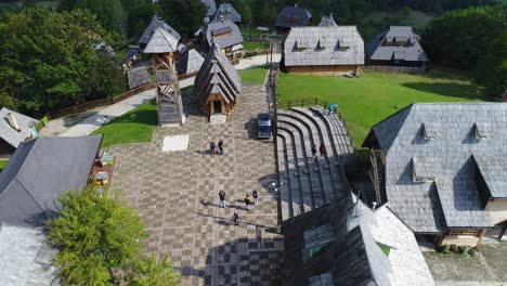 Kustendorf-Village-main-street-with-people-taking-pictures-in-front-of-the-St-Sava-Church,-Aerial-dolly-in-reveal-shot