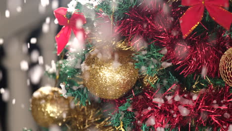 Detail-on-golden-Christmas-ball-on-the-tree-with-snow-falling