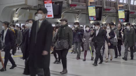 Personas-Con-Máscaras-Durante-La-Hora-Pico-En-La-Estación-De-Shinagawa-En-Tokio,-Japón---Tiro-De-Tele-Medio