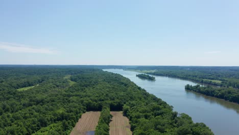 Flying-over-beautiful-farmland-and-trees-with-the-Potomac-river-cutting-through-the-middle-drone-aerial
