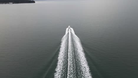 A-lone-boat-speeds-through-the-dark-gray-green-waters-of-Puget-Sound-and-the-Salish-Sea,-aerial