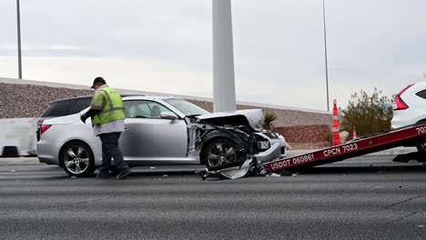 Tow-truck-driver-hooks-up-car-to-be-loaded-on-flatbed