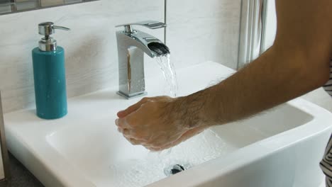 Male-rinsing-soap-off-of-hands-and-arms-in-a-bathroom-sink-in-super-slow-motion