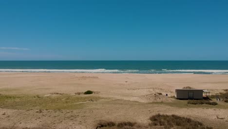 Drohne-Bewegt-Sich-Auf-Einer-Einstöckigen-Hausstruktur-Am-Küstenstrand-Von-Rocha,-Uruguay