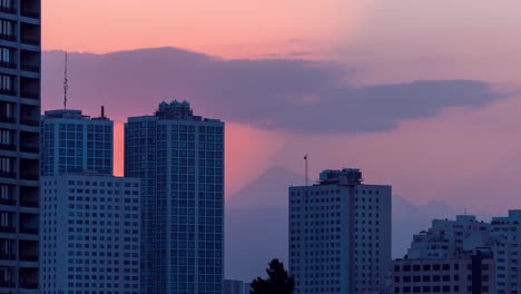 Atemberaubender-Sonnenaufgang-Hinter-Dem-Berggipfel-Des-Damavand-Vulkans-In-Teheran,-Iran,-Mit-Schatten-Des-Sonnenstrahls-Hinter-Den-Gebäuden.-Silhouette-Am-Gelb-orangefarbenen-Himmel-Am-Frühen-Morgen-Mit-Einigen-Wolken