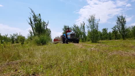 Hombre-Operando-Tractor-Con-Henificador-De-Heno-En-El-Prado---Disparo-De-Bajo-Nivel