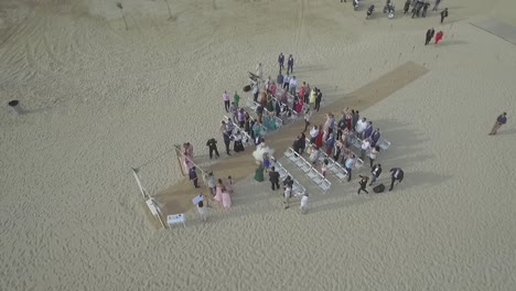 Novia-Y-Novio-Caminando-Por-El-Pasillo-En-La-Ceremonia-De-Boda-En-La-Playa,-De-Arriba-Hacia-Abajo,-Dando-Vueltas-Aéreas