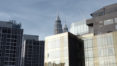 Aerial-Shot-Of-Model-In-Infinity-Pool-And-Petronas-Twin-Towers-In-Kuala-Lumpur,-Malaysia