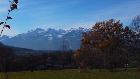 Montaña-Nevada-De-Los-Alpes-De-Austria-Y-Suiza-Con-Un-Amplio-Paisaje-Y-Hojas-De-Otoño-Más-Cielo-Azul