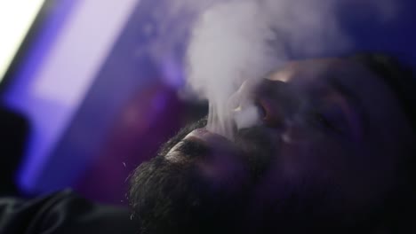 Slow-panning-rotation-around-male-with-beard-exhaling-vape-smoke