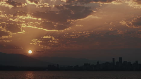 Sun-rises-from-mountains-over-Vancouver-Skyline-with-beautiful-clouds,-Time-lapse