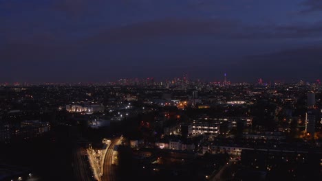 Aerial-dolly-forward-drone-shot-towards-central-London-Skyline-over-residential-buildings-at-night