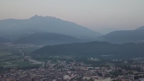 Aerial-panoramic-view-of-Levico-Terme,-Italy,-during-sunrise-with-drone-panning-left-to-right
