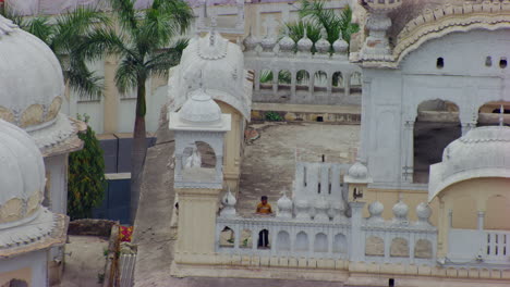 Una-Vista-De-Drones-De-Cerca-De-Los-Minaretes-Del-Templo-Sikh,-Un-Niño-Sikh-Mirando-Desde-La-Parte-Superior-Del-Templo,-Templo-Blanco