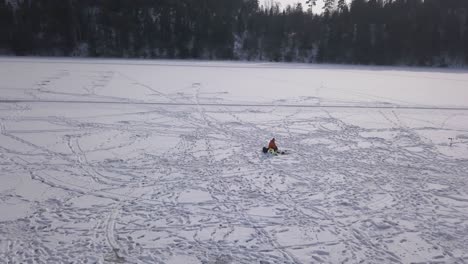 Rückwärtsfahrt-Eines-Einsamen-Fischers,-Der-Geduldig-Neben-Seinem-Loch-Im-Eis-Darauf-Wartet,-Dass-Etwas-Anbeißt