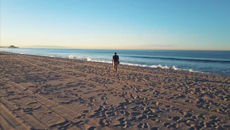 Man-walks-on-beach-alone-towards-sunset-or-sunrise