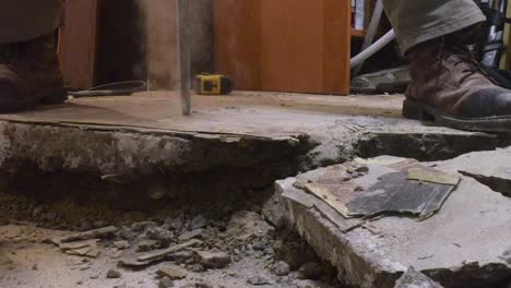 Medium-shot-of-concrete-drill-penetrating-basement-concrete-floor,-with-debris-and-smoke-coming-out-of-bit-head
