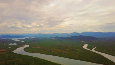 Panning-drone-view-of-landscape-of-a-river-in-a-valley-with-mountains-in-the-background-on-a-cloudy-day