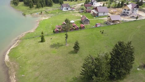 Aerial-Take-off-Shot-of-Lake-Edge-with-ever-green-trees-and-building-site