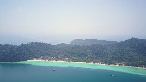 Aerial-view-of-lush-island-with-accommodation-by-the-beach-in-Thailand---camera-panning