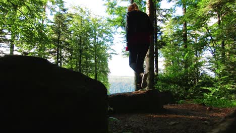 Young-female-hiker-with-camera-walking-along-a-trail-in-the-Black-Forest-around-Mount-Sommerberg