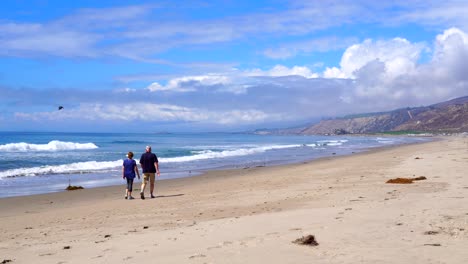 Couple-walking-along-the-beach-at-Rincon-Parkway-in-California