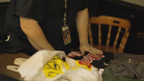 Man-folding-shirts-on-a-table-at-a-thrift-store