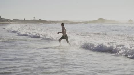 Cámara-Lenta:-El-Hombre-En-Pantalones-Cortos-Se-Queda-Sin-El-Océano-En-Camps-Bay,-Sudáfrica