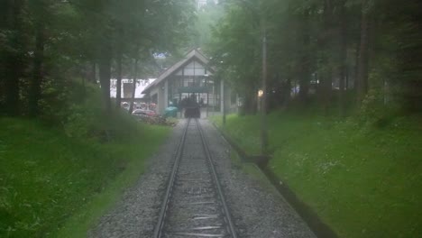 A-funicular-pulls-into-the-station-having-travelled-through-a-dark,-tranquil-and-mysterious-forest