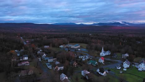 Aerial-footage-flying-over-small-rural-community-in-late-fall-at-sunrise-with-misty-mountains-in-the-distance