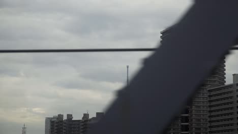 Reveal-view-of-Tokyo-Skytree-behind-residential-building-from-train-window