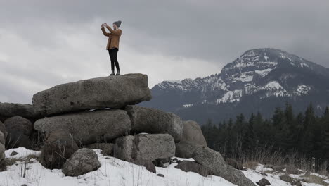 A-girl-takes-pictures-of-the-snowy-mountains-around-her