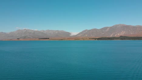 Luftaufnahme-Des-Lake-Tekapo,-Neuseeland-Und-Seines-Wunderschönen-Türkisblauen-Wassers-Mit-Bergen-Im-Hintergrund