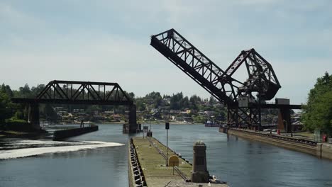 Time-Lapse-of-boats-exiting-and-entering-the-Ballard-Locks,-train-trestle-is-open-in-background
