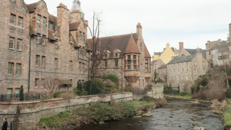 Pan-right-to-left-over-the-Water-of-Leith-river-to-Dean-Village-Well-Court-on-an-overcast-day-in-Edinburgh,-Scotland