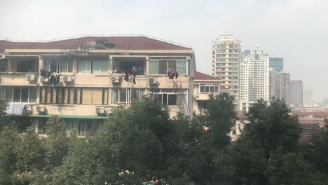 Sunny-daylight-on-a-three-story-townhouse-in-South-Shanxi-Road-with-modern-high-rise-buildings-in-the-background-as-a-typical-mix-of-the-two-worlds-in-Shanghai