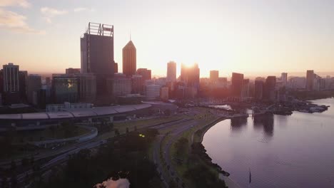 Vista-Aérea-De-Un-Horizonte-De-Perth-Al-Amanecer-Con-Movimiento-De-Cámara-Hacia-Adelante-Hacia-Las-Torres-Y-El-Puerto-De-Autobuses