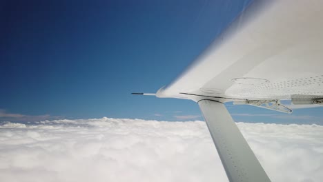 Nahaufnahme-Eines-Kleinen-Flugzeugflügels,-Der-über-Geschwollenen-Weißen-Wolken-Und-Blauem-Himmel-Fliegt