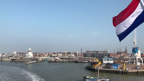 Beautiful-typical-Dutch-harbour-village-with-flag-and-material-transportation-boat