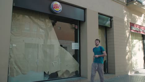 Young-man-walks-past-temporarily-closed-Burger-King-in-Seville,-Spain