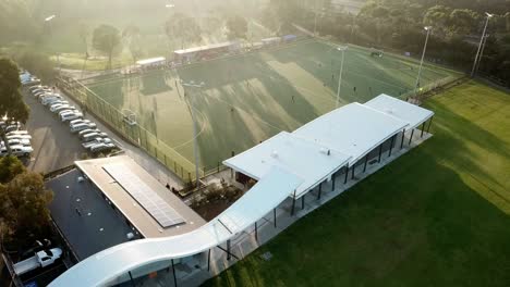 Rising-aerial-drone-footage-into-the-sun-of-a-men's-premier-league-field-hockey-match-at-Elgar-Park