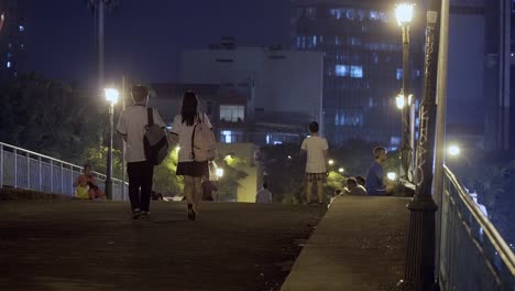 Student-Couple-in-Uniform-Walking-on-a-Bridge-at-Night