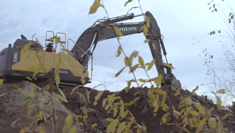 Dramatic-low-angle-shot-of-excavator-digging-in-mud-and-gravel,-Volvo-EC380EL