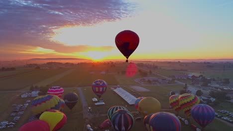 Luftaufnahme-Eines-Morgendlichen-Starts-Von-Heißluftballons-Bei-Einem-Ballonfestival-Vom-Befüllen-Bis-Zum-Abheben,-Wie-Von-Einer-Drohne-Gesehen