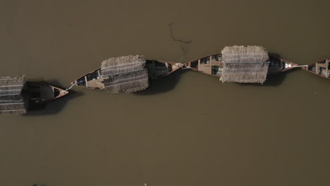 Toma-Aérea-De-Arriba-Hacia-Abajo-De-Una-Fila-De-Viejos-Barcos-De-Pesca-Fluviales-De-Estilo-Tradicional-En-Un-Canal-Hoang-Sa-En-El-Distrito-De-Binh-Thanh-De-La-Ciudad-De-Ho-Chi-Minh-O-Saigon-Vietnam