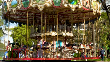 Niños-Divirtiéndose-Montando-Caballos-En-Un-Tiovivo-Clásico-Girando-En-Un-Parque