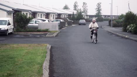 Dramatische-Zeitlupe-Einer-Oma,-Die-In-Einem-Nebligen,-Verlassenen-Dorf-Fahrrad-Fährt