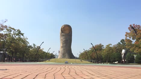 La-Gente-Da-Un-Paseo-Cerca-De-Una-Gran-Escultura-En-El-Parque-Olímpico,-Oryun-dong,-Songpa-gu,-Seúl,-Corea-Del-Sur